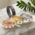 Thea - Anillo antiestrés giratorio con huellas de colores