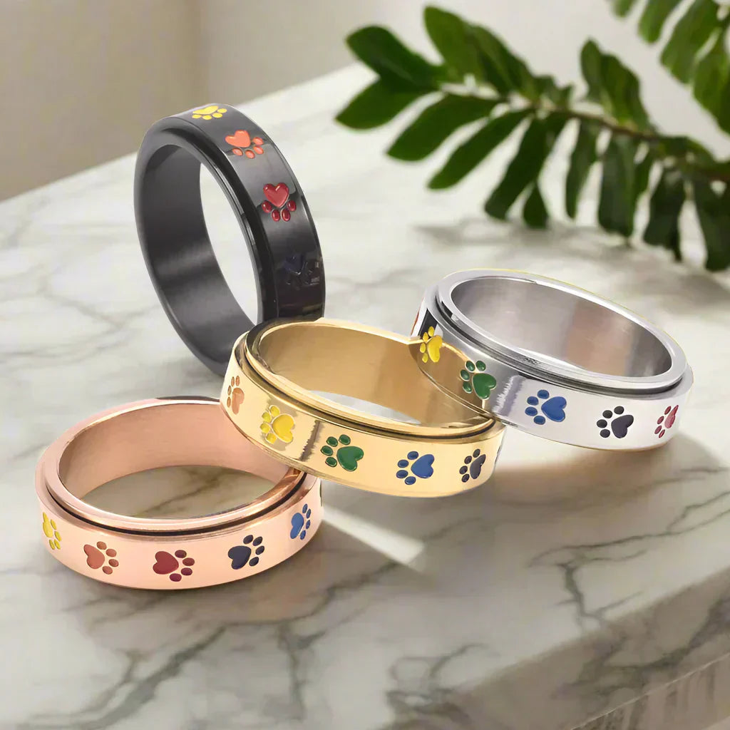 Thea - Anillo antiestrés giratorio con huellas de colores